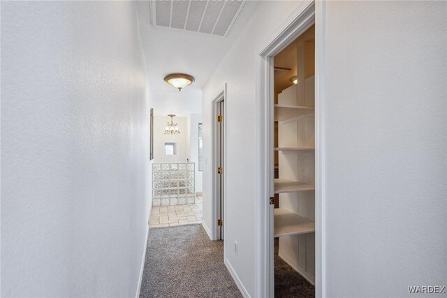 corridor with baseboards, visible vents, stairway, dark carpet, and a notable chandelier