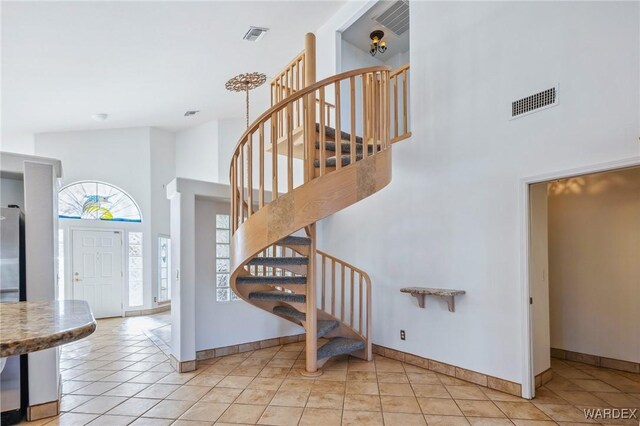 stairway featuring tile patterned flooring, a high ceiling, visible vents, and baseboards