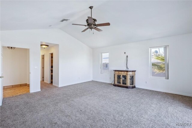 unfurnished living room featuring vaulted ceiling, carpet flooring, visible vents, and a healthy amount of sunlight