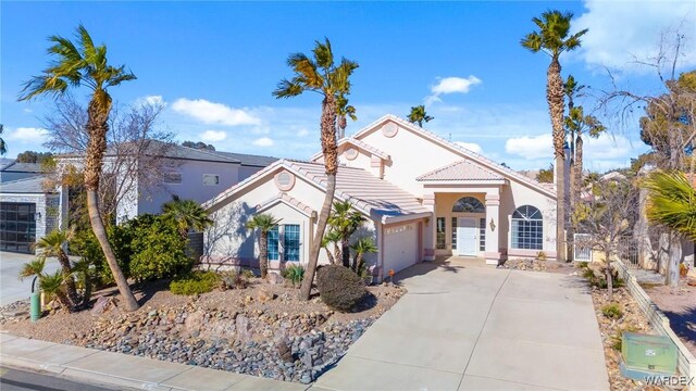 mediterranean / spanish-style house featuring concrete driveway, a tile roof, an attached garage, and stucco siding