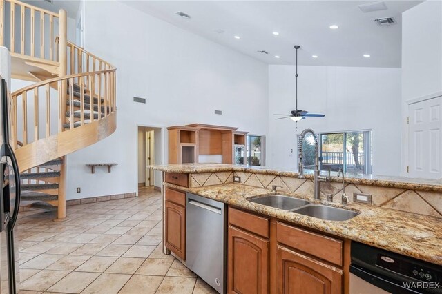 kitchen featuring brown cabinets, dishwasher, a sink, and light tile patterned floors