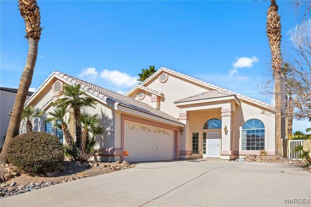 mediterranean / spanish-style home with a garage, a tile roof, concrete driveway, and stucco siding