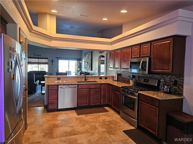 6246 S Vista Laguna Dr, Fort Mohave, AZ 86426 - kitchen with stainless steel appliances, a peninsula, a sink, tasteful backsplash, and light stone counters