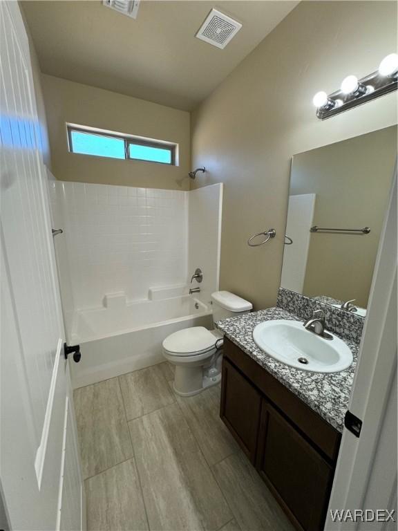 bathroom with toilet, bathing tub / shower combination, vanity, and visible vents