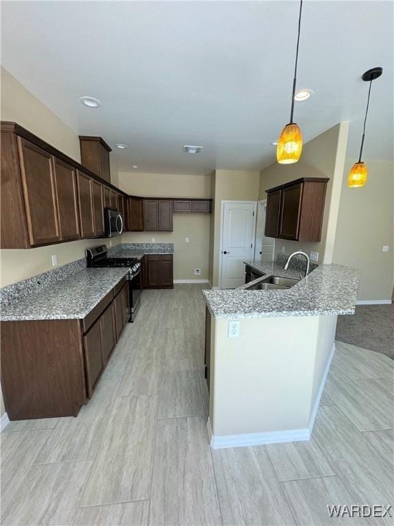 kitchen with visible vents, stainless steel appliances, dark brown cabinets, pendant lighting, and a sink