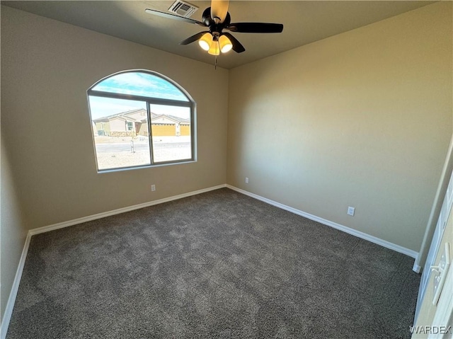 empty room featuring baseboards, visible vents, dark colored carpet, and a ceiling fan