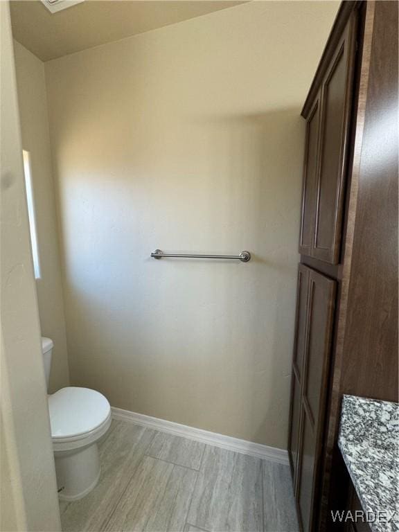 bathroom with baseboards, toilet, and wood finished floors