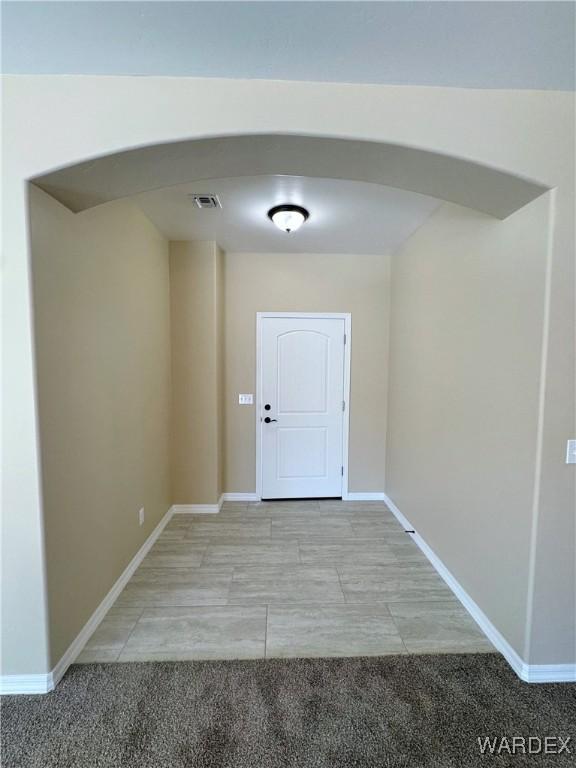 interior space with baseboards, visible vents, and arched walkways