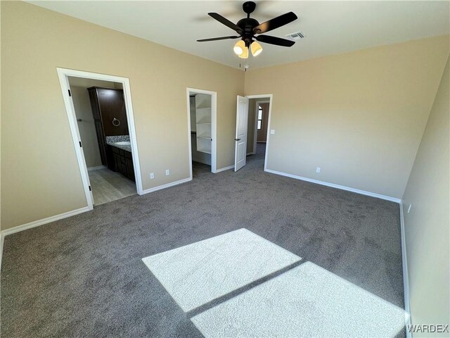 unfurnished bedroom with carpet floors, baseboards, and a walk in closet