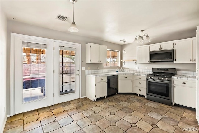 kitchen featuring stainless steel appliances, light countertops, decorative light fixtures, and white cabinets