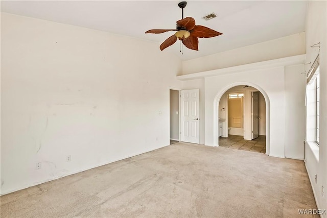 unfurnished bedroom with light carpet, ensuite bath, arched walkways, and visible vents