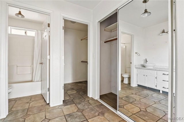 bathroom featuring vanity, shower / bath combination, a walk in closet, and toilet