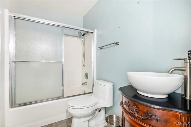 full bathroom featuring toilet, shower / bath combination with glass door, and a sink