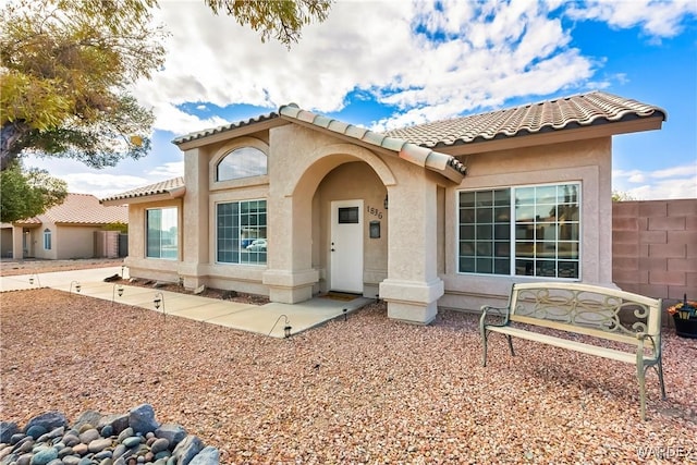 view of front of house with a tiled roof, fence, and stucco siding