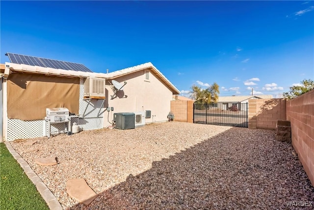 rear view of property featuring a gate, fence, central AC, and stucco siding