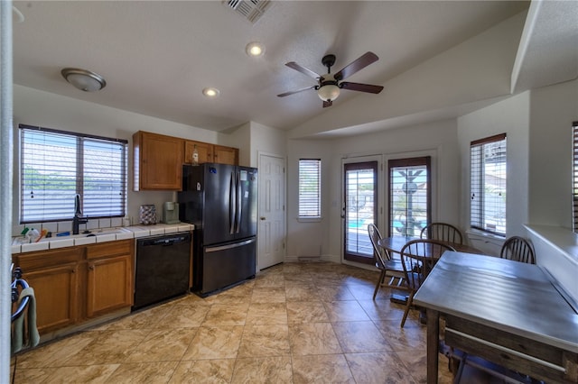 2041 E Sundance Dr, Fort Mohave, AZ 86426 - kitchen with black appliances, tile countertops, brown cabinets, vaulted ceiling, and plenty of natural light