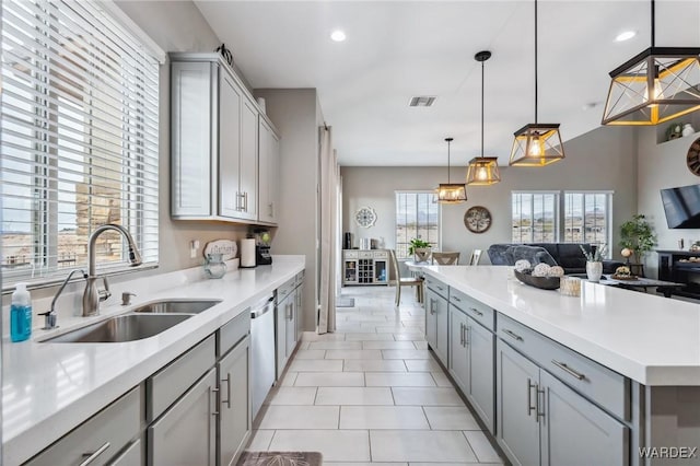 kitchen with open floor plan, decorative light fixtures, gray cabinets, light countertops, and a sink