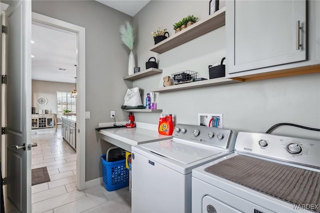 clothes washing area featuring washing machine and dryer and cabinet space