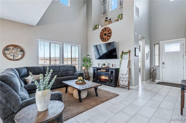 living area with light tile patterned floors, visible vents, baseboards, and a glass covered fireplace