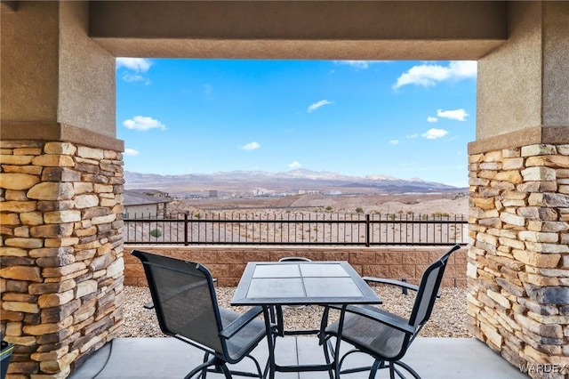 balcony with a patio, outdoor dining area, and a mountain view