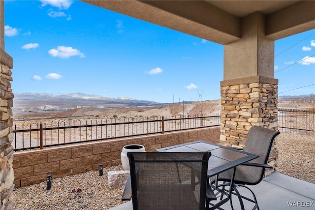 view of patio / terrace featuring fence, a mountain view, and outdoor dining space