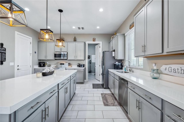 kitchen featuring visible vents, appliances with stainless steel finishes, gray cabinets, light countertops, and a sink