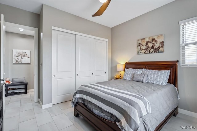 bedroom with light tile patterned floors, a ceiling fan, baseboards, and a closet