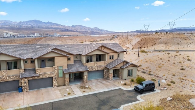 view of front facade featuring stone siding, a mountain view, and concrete driveway