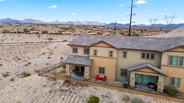 rear view of house featuring a mountain view, fence, central AC unit, and stucco siding