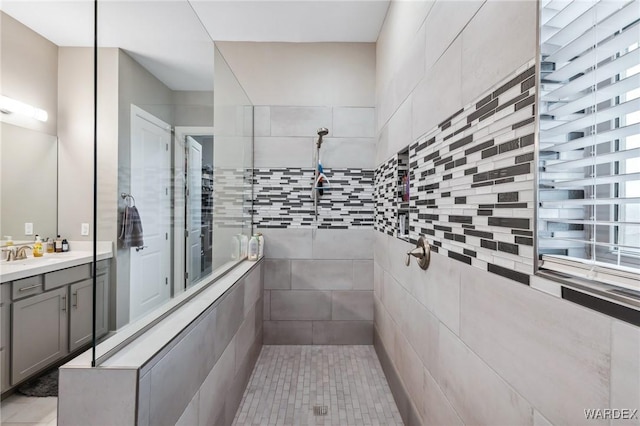 bathroom with tiled shower and vanity