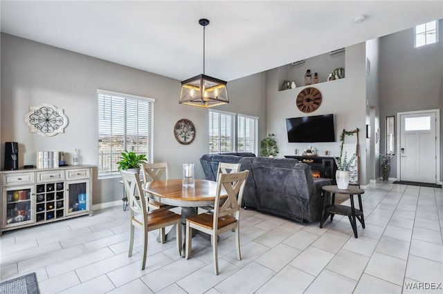 dining area with light tile patterned flooring, plenty of natural light, baseboards, and an inviting chandelier