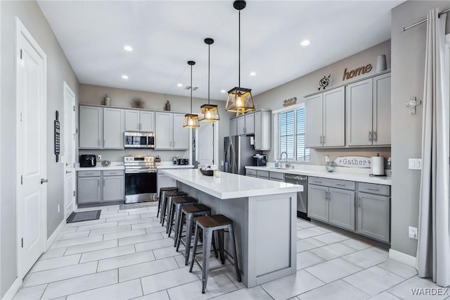 kitchen with a breakfast bar, light countertops, appliances with stainless steel finishes, hanging light fixtures, and a center island