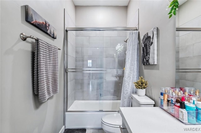 bathroom with combined bath / shower with glass door, vanity, and toilet