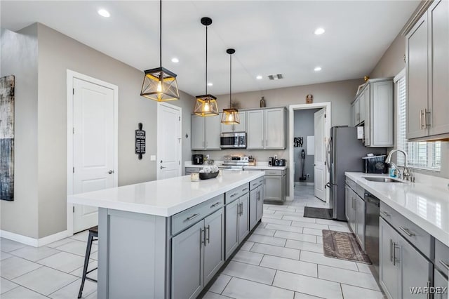 kitchen with light countertops, appliances with stainless steel finishes, hanging light fixtures, and a sink