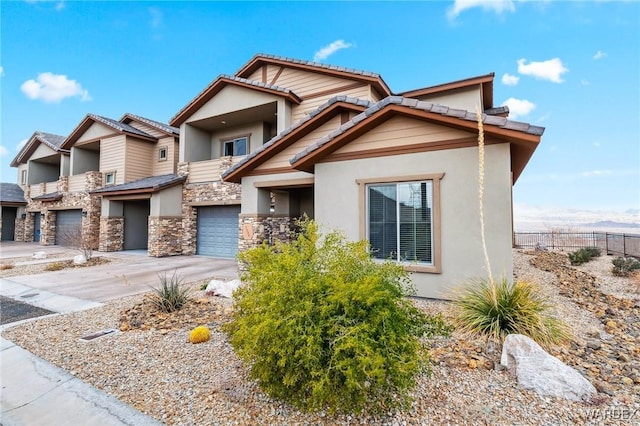 view of front of home with a garage, driveway, stone siding, and stucco siding