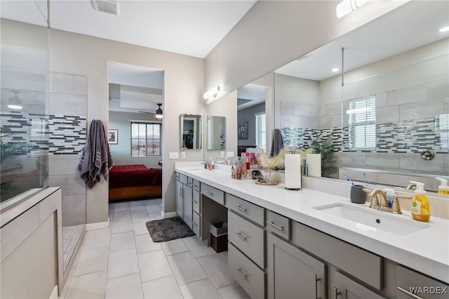 ensuite bathroom featuring plenty of natural light, a sink, ensuite bath, and double vanity