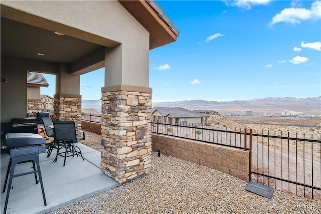 view of patio / terrace with fence and a mountain view