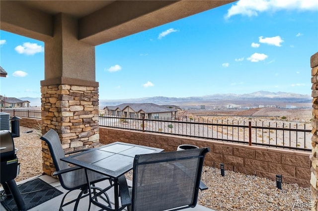 view of patio / terrace featuring outdoor dining space, central air condition unit, a mountain view, and fence