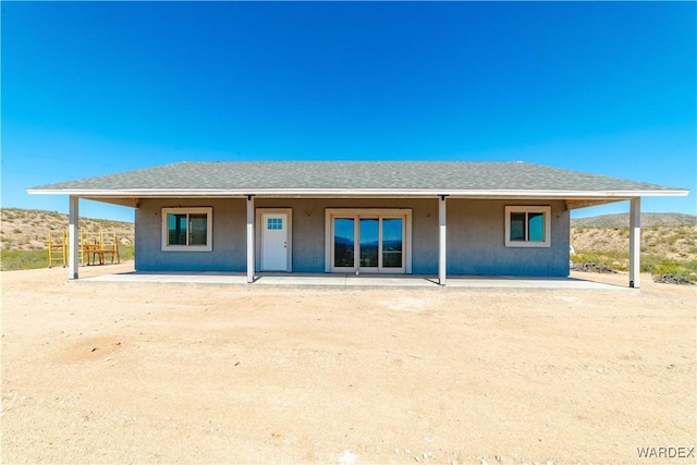 back of property with roof with shingles, a patio, and stucco siding