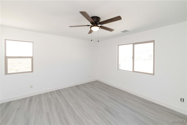 spare room with baseboards, visible vents, light wood-style flooring, and a wealth of natural light