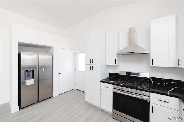 kitchen featuring wall chimney range hood, dark countertops, appliances with stainless steel finishes, and white cabinets