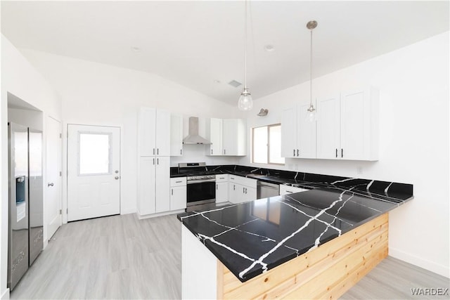 kitchen with stainless steel appliances, a peninsula, white cabinetry, hanging light fixtures, and wall chimney exhaust hood