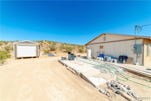 view of patio with a detached garage and driveway