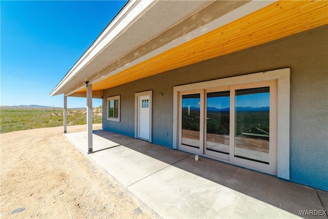 view of side of home with stucco siding and a patio