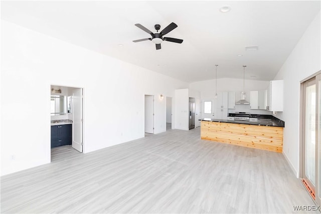 kitchen featuring white cabinets, wall chimney exhaust hood, open floor plan, decorative light fixtures, and stainless steel stove