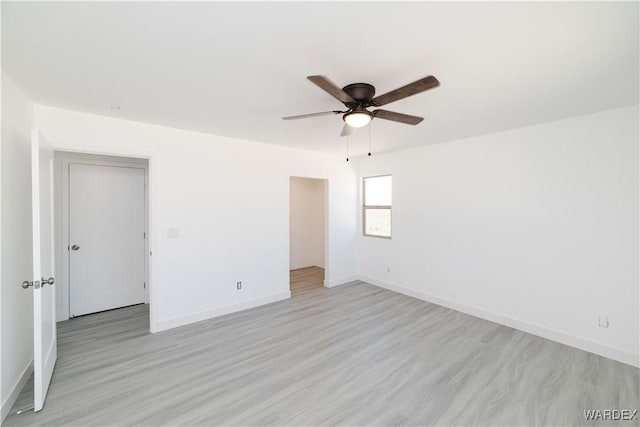 spare room featuring ceiling fan, light wood-style flooring, and baseboards