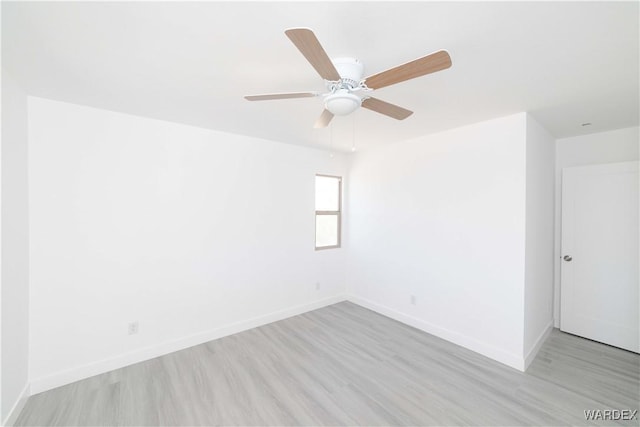 spare room featuring light wood-style floors, baseboards, and a ceiling fan