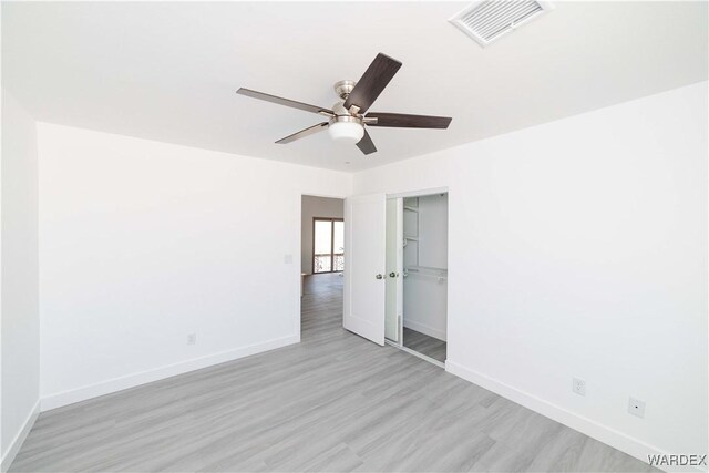 spare room featuring light wood-style floors, baseboards, visible vents, and a ceiling fan