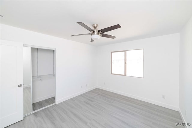 unfurnished bedroom with light wood-type flooring, a ceiling fan, baseboards, and a closet