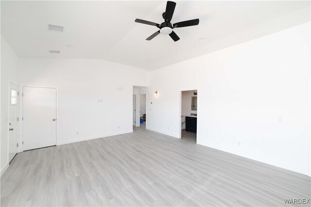 spare room with light wood finished floors, visible vents, a ceiling fan, vaulted ceiling, and baseboards